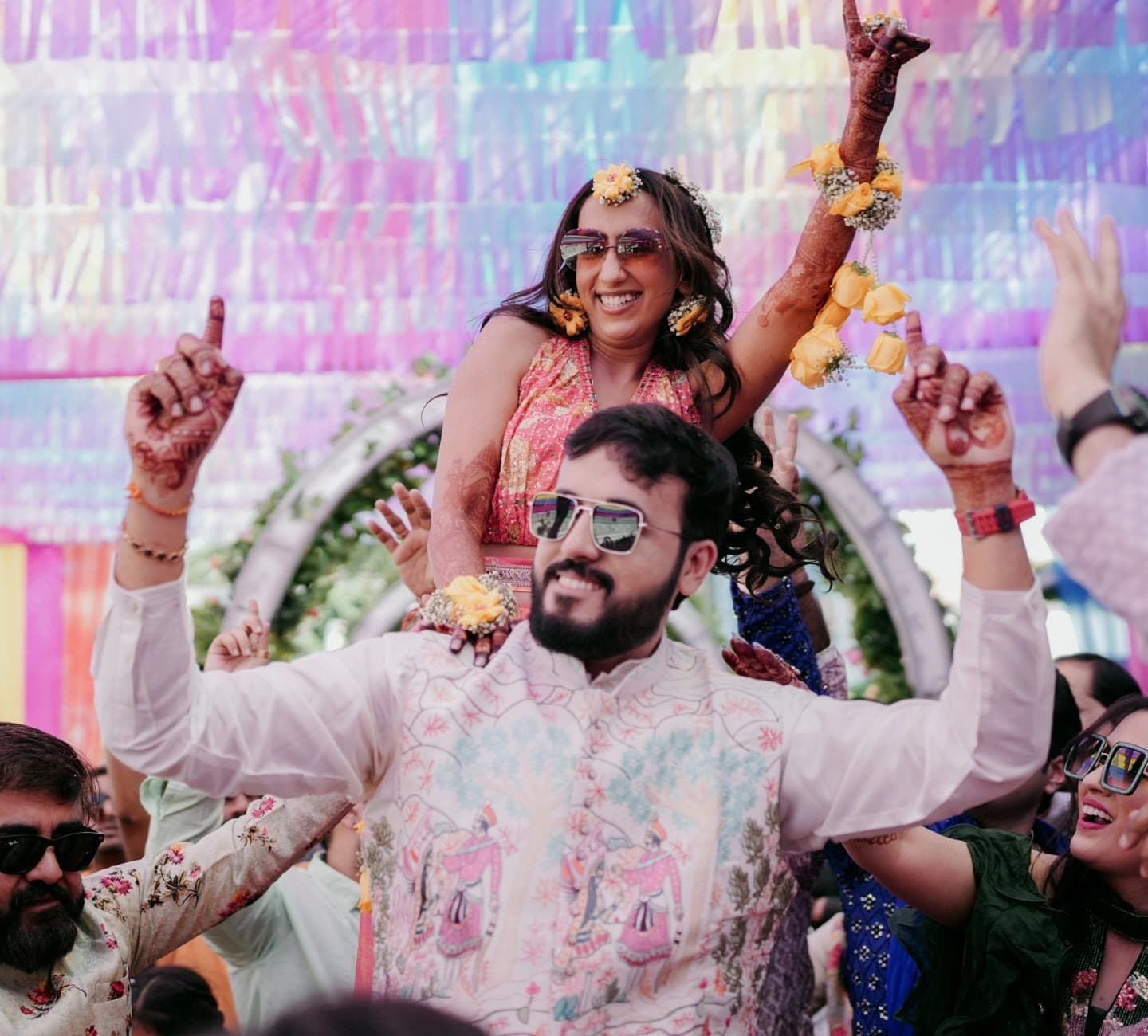 Bride and groom celebrating on shoulders at their mehendi function