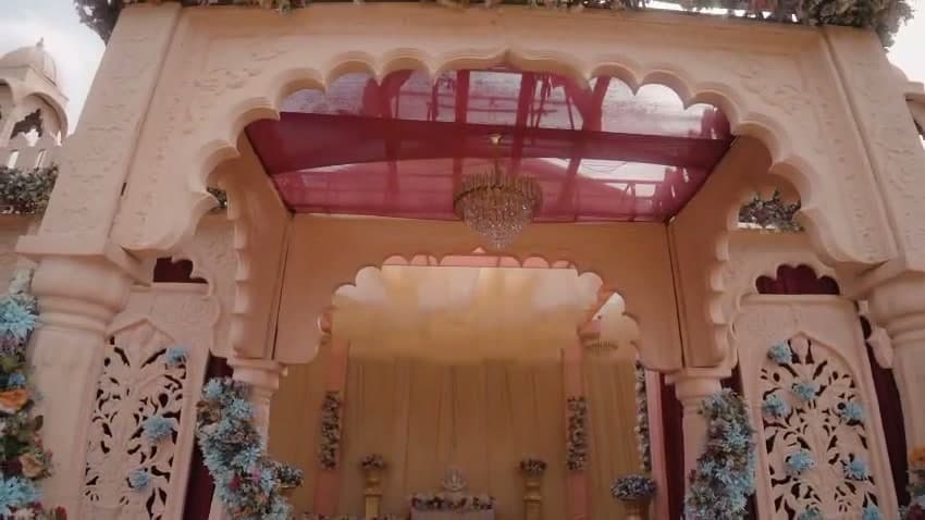 Close view of the ivory palace gateway with a scalloped arch, pink draped ceiling and floral trim framing the entry inside