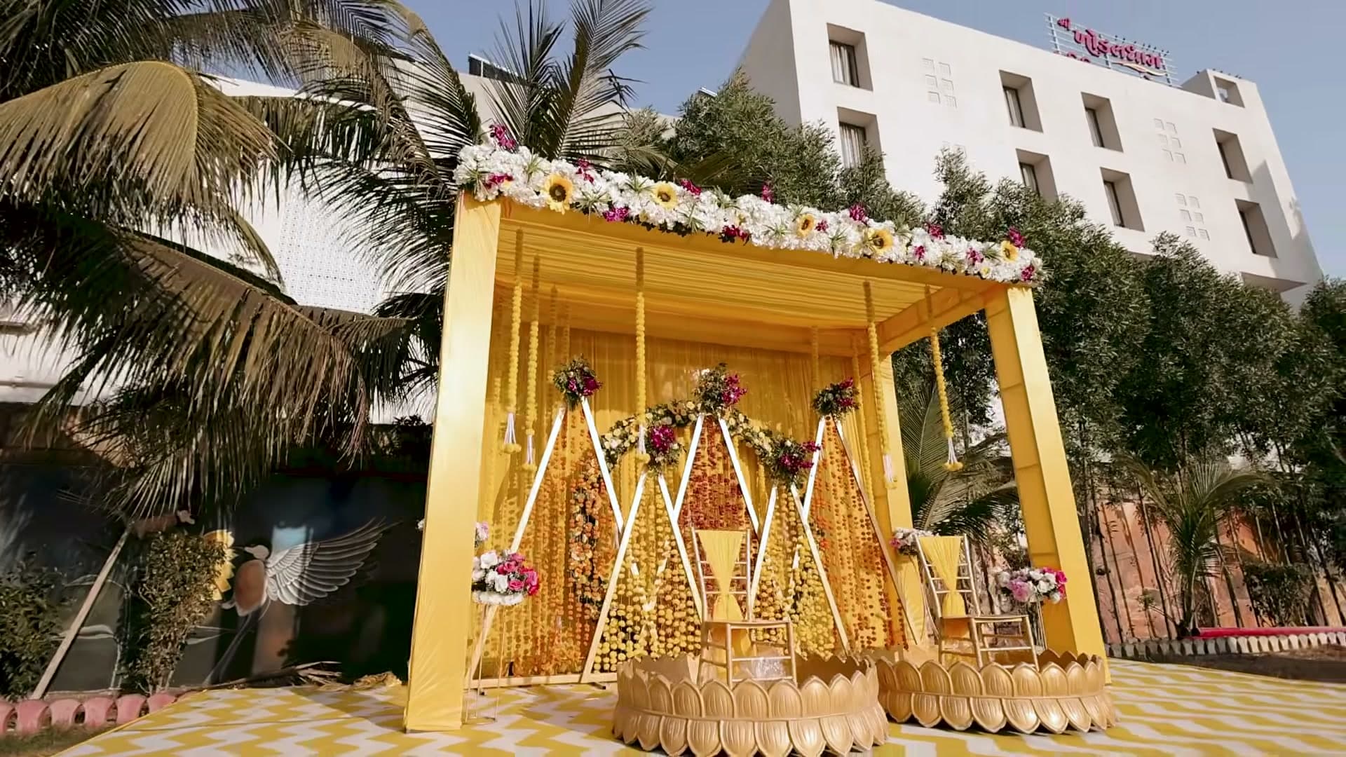 Marigold-draped mandap in yellow and gold, with hanging floral garlands over two lotus-shaped ceremony seats.