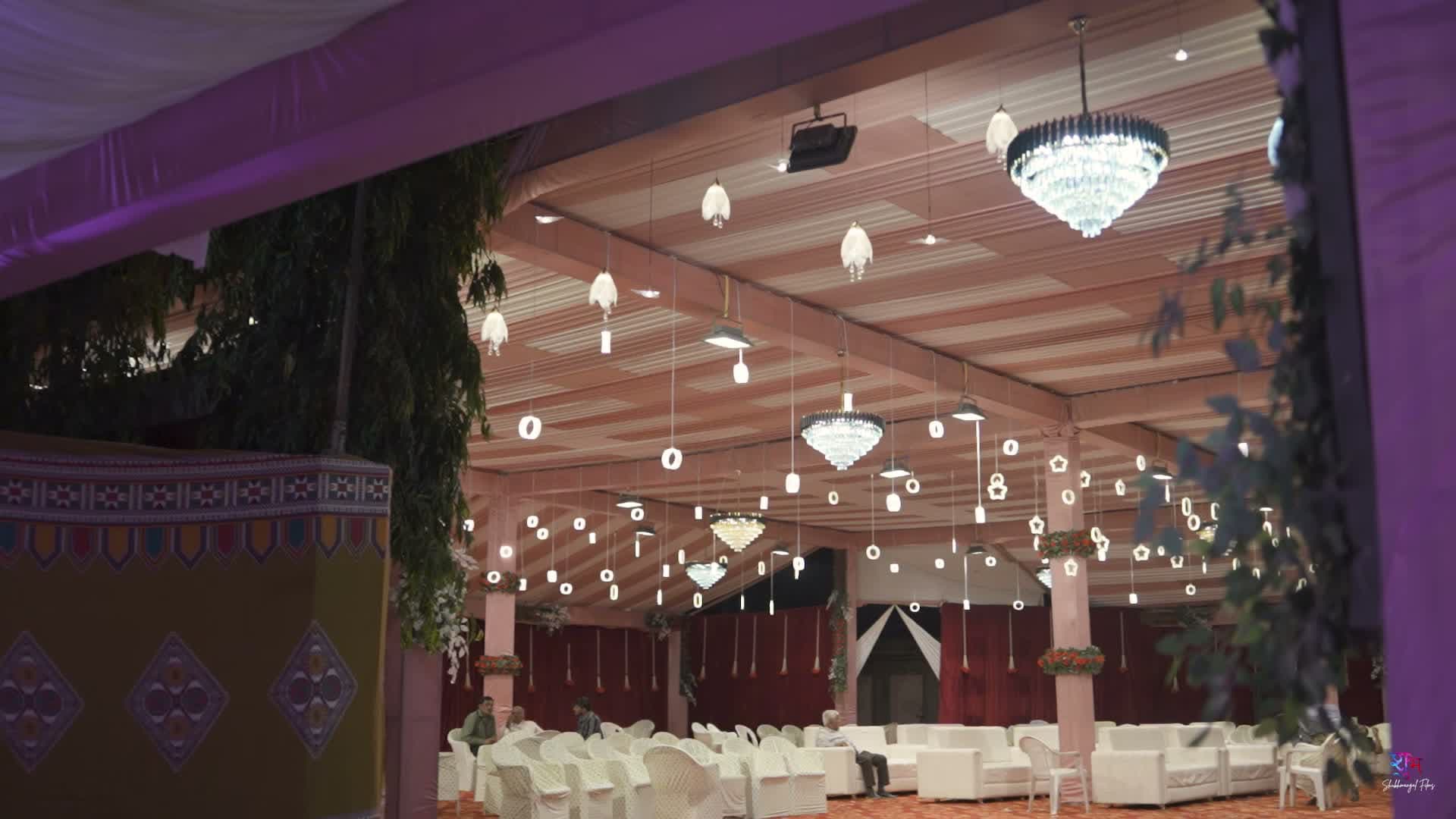 Wide view of the reception hall interior with rows of hanging crystal chandeliers, star ornaments, and lounge seating — Keshod, Gujarat